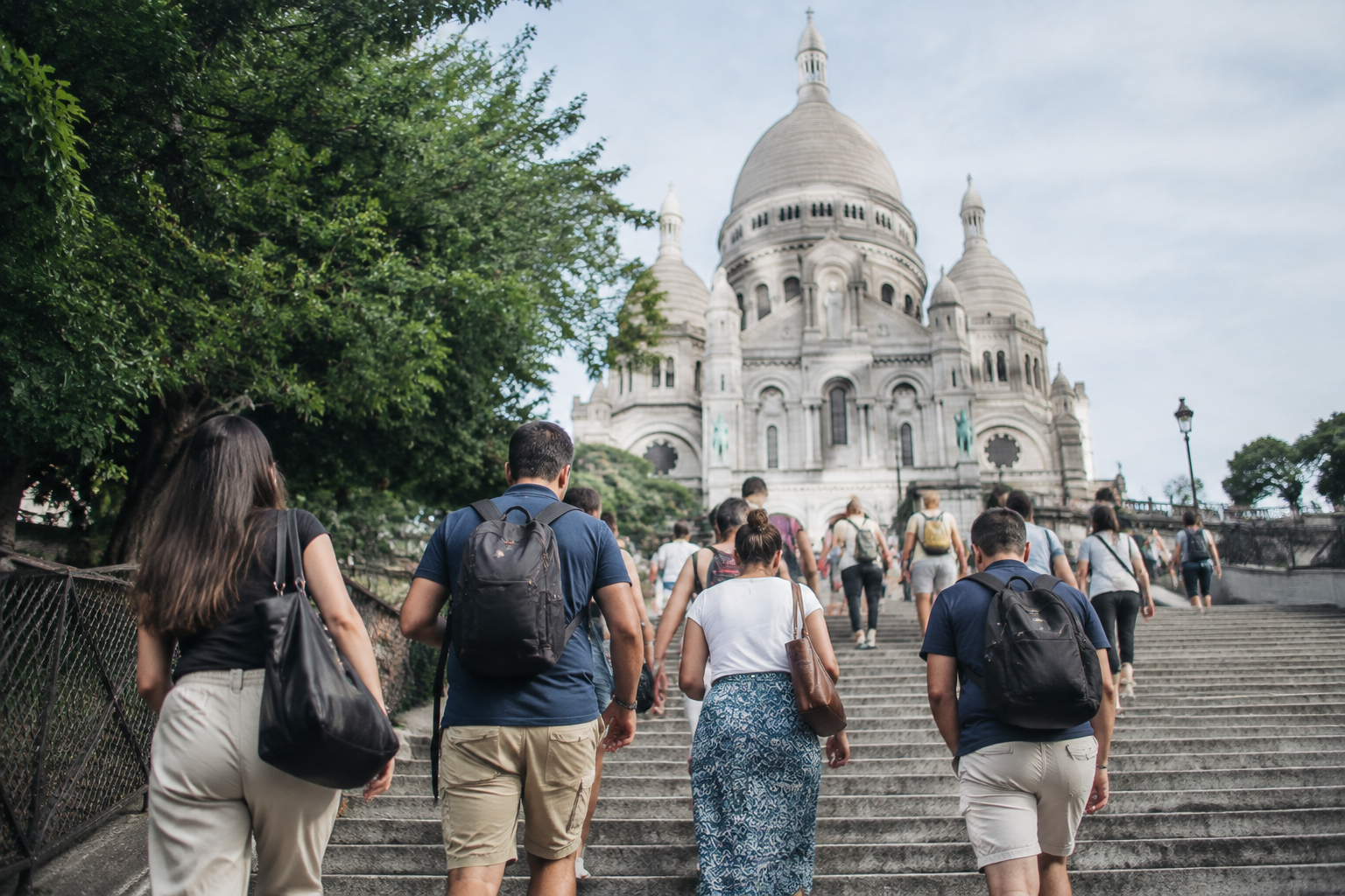 Touristes montent escaliers direction basilique blanche surplomb